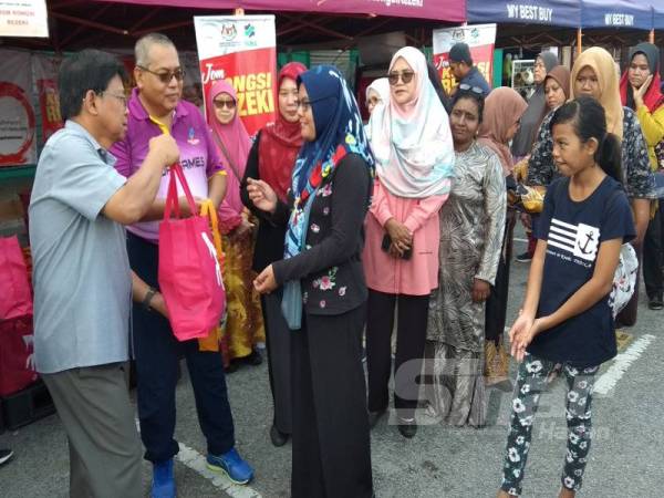 Zainal Abidin (dua dari kiri) bersama Asmuni (kiri) menyampaikan sumbangan berbentuk barangan keperluan program Jom Kongsi Rezeki pada Program MyBest Buy FAMA @ LTdL 2020 di Bandar Meru Raya hari ini. 