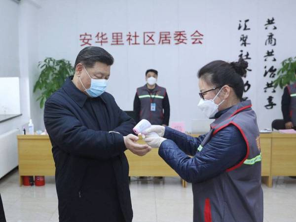 Pihak berkuasa kesihatan memeriksa suhu tubuh Presiden China, Xi Jinping ketika beliau berkunjung di Pusat Kawalan dan Pencegahan Koronavirus di Komuniti Anhuali di Beijing semalam. - FOTO: AFP