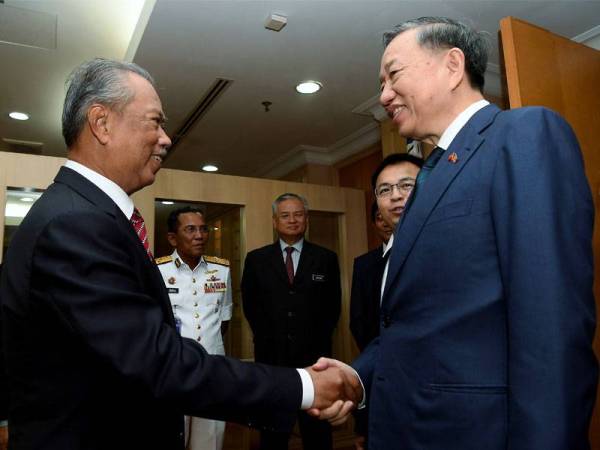 Muhyiddin (kiri) bersalaman dengan To Lam ketika menerima kunjungan hormat Menteri Keselamatan Awam Vietnam itu di Kementeriannya di Putrajaya semalam. - Foto Bernama