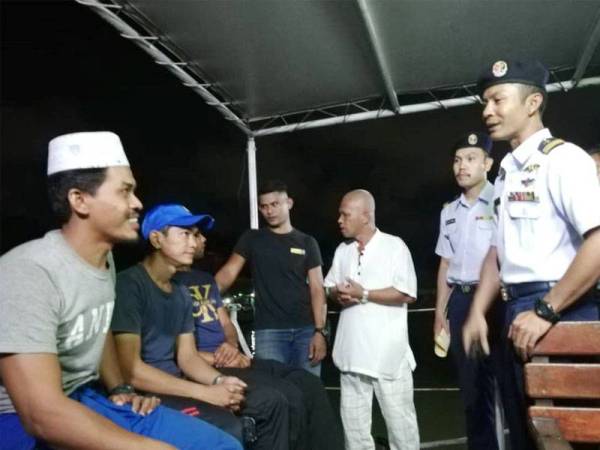 Timbalan Pengarah (Operasi) Maritim Terengganu, Komander Maritim Ariffin Ghazali (kanan) bertanya khabar Azwan (kiri) dan rakan-rakan yang diselamatkan sejurus tiba di jeti APMM Terengganu, di Pulau Kambing, di sini, malam tadi.