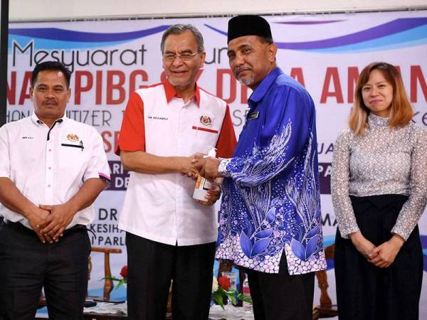 Dr Dzulkefly (dua dari kiri) melakukan simbolik penyerahan 'hand sanitizer' kepada Guru Besar SK Desa Aman Shahidan Said (dua dari kanan) selepas merasmikan Mesyuarat Agung Tahunan PIBG SK Desa Aman Kali Ke-9 di Sungai Buloh hari ini. Foto: Bernama