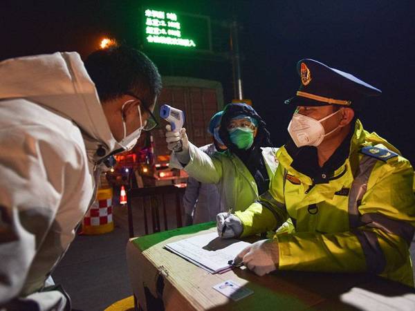 Pihak berkuasa memeriksa suhu seorang pemandu bas di laluan keluar lebuh raya Zhangjiakou di utara wilayah Hubei. - AFP