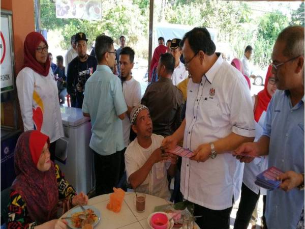 Eddin (dua dari kanan) mengedarkan risalah pada Program Info On Wheels (IOW) bersama Jabatan Penerangan Terengganu di Pasar Awam Binjai Rendah di sini hari ini.