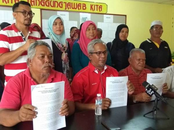 Mazlan (duduk, dua dari kiri) menunjukkan kenyataan media bersama-sama ahli-ahli Bersatu Bahagian Beruas yang mahu pemilihan parti yang berlangsung esok ditangguhkan.