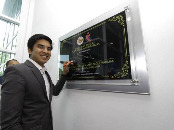 Syed Saddiq menurunkan tandatangan sebagai merasmikan bangunan baharu Pusat Belia Antarabangsa (IYC) hari ini. - Foto Bernama