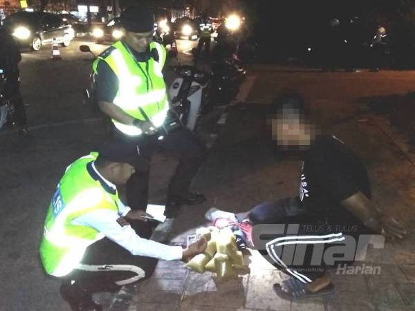 Anggota trafik memeriksa cecair disyaki ketum yang dibawa remaja ketika operasi sekatan jalan malam tadi. 