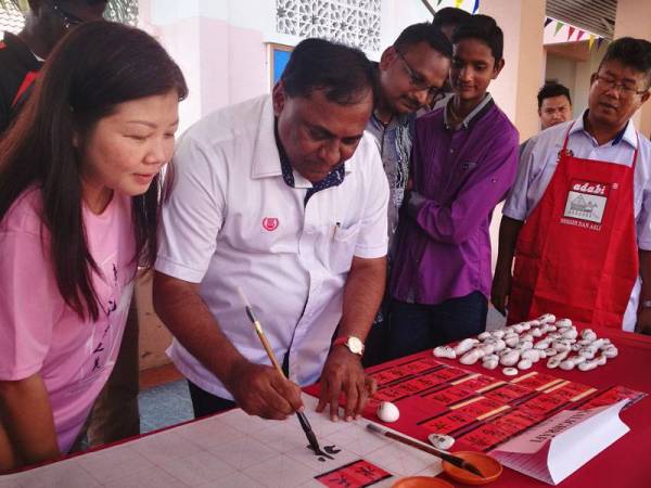 Summugam turut meluangkan masa cuba menulis tulisan kaligrafi Cina.