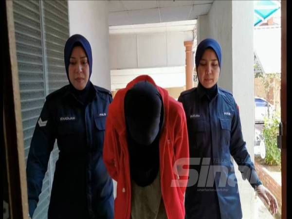 Tertuduh diiringi polis sewaktu tiba di Mahkamah Sesyen Kuala Terengganu hari ini.