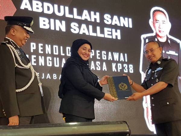 Haslina sambil diiringi Siful Yazan menyampaikan APC kepada warga Maqis pada majlis di Dewan Serbaguna MOA, Putrajaya.