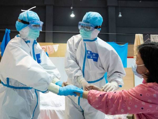 Pekerja perubatan memeriksa pesakit dengan terapi perubatan tradisional Cina (TCM) di sebuah hospital sementara di Daerah Jiangxia di Wuhan. Foto: Xinhua