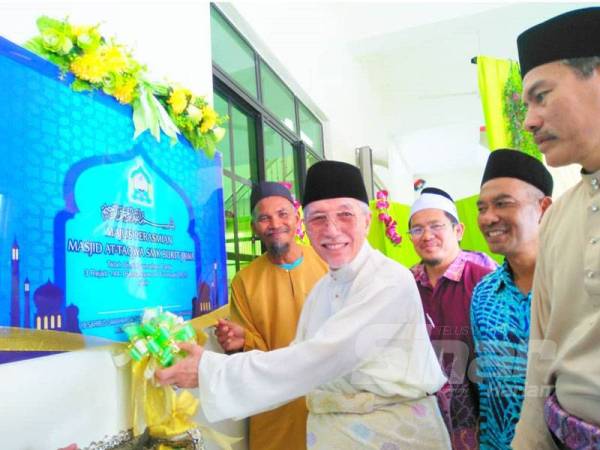 Mohamad Shukri (kiri) memotong reben sebagai simbolik merasmikan pembukaan Masjid At-Taqwa SMK Bukit Jawa sambil disaksikan oleh Azman (kanan).