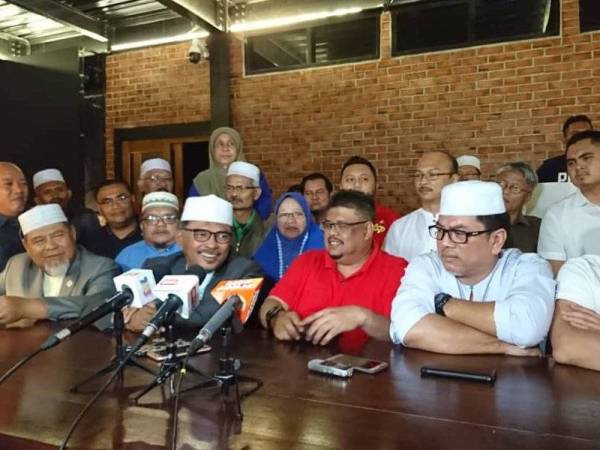 Idris dan Ab Rauf (tengah) bersama barisan kepimpinan Badan Perhubungan UMNO negeri di kediamannya di Kampung Pulau Semut, di Masjid Tanah, di sini, tadi.