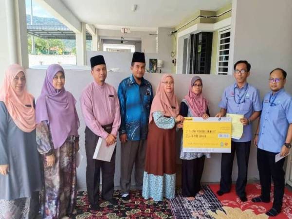 Redhuan (dua dari kanan) menyerahkan cek berjumlah RM2,000 kepada Naemah (tiga dari kanan) pada Majlis Penyerahan Cek Pengurusan Jenazah di Taman Sri Rembau semalam.