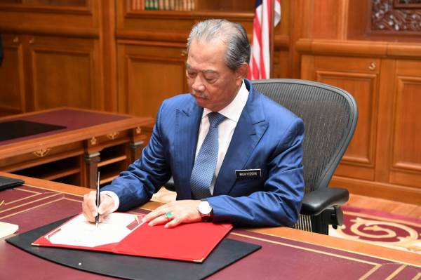 Muhyiddin menandatangani buku selamat datang dan selamat bertugas di Perdana Putra hari ini. -Foto Bernama