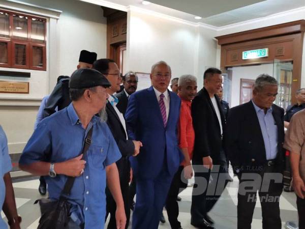 Najib (tengah) ketika keluar dari mahkamah selepas prosiding perbicaraan ditangguh esok.