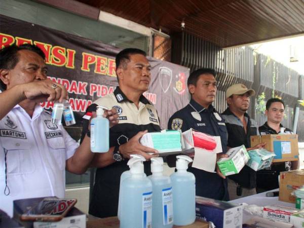 Iskandar F Sutisna (dua dari kiri) bersama pegawai lain menunjukkan topeng muka dan pencuci tangan yang dirampas. - Foto Agensi