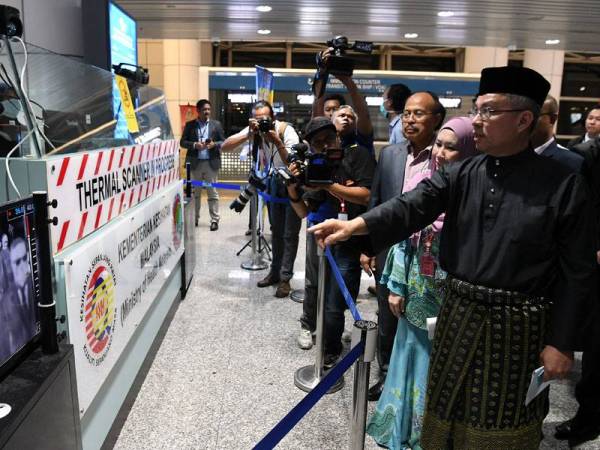 Dr Adham (kanan) melihat mesin pengimbas termal yang berada di balai ketibaan semasa melakukan lawatan pertamanya ke Lapangan Terbang Antarabangsa Kuala Lumpur (KLIA) bagi meninjau mesin saringan yang terdapat di lapangan terbang berkenaan. - Foto Bernama