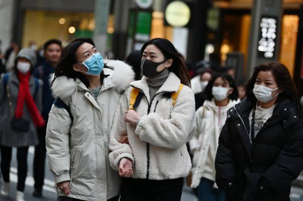 Pejalan kaki memakai topeng muka ketika berjalan di kawasan Ginza, Tokyo, Jepun.