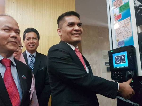 Mohd Radzi mengimbas cap jari pada mesin 'clock in' sebagai simbolik beliau melapor diri secara rasmi di Kementerian Pendidikan di Putrajaya hari ini.