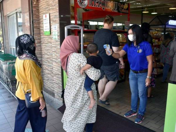  Kelihatan seorang pekerja sebuah pasaraya di Tawau sedang memeriksa bacaan suhu kepada setiap pelanggan di pintu masuk- fotoBERNAMA