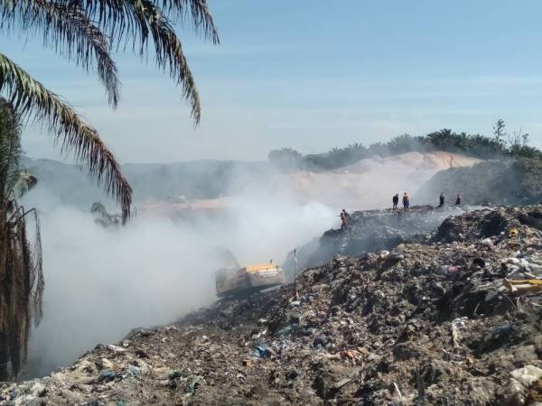 Anggota bomba sedang berusaha memadamkan api kebakaran di tapak sampah haram.