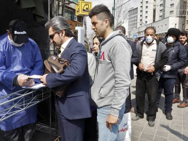 Orang ramai beratur untuk menerima pakej langkah berjaga-jaga yang disediakan oleh Basij, salah satu pasukan bersenjata Pengawal Revolusi Islam Iran di Teheran. - Foto AFP