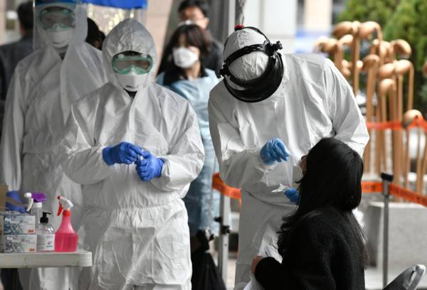 
Pasukan perubatan mengambil sampel daripada seorang wanita di kemudahan ujian sementara di Seoul, Korea Selatan.