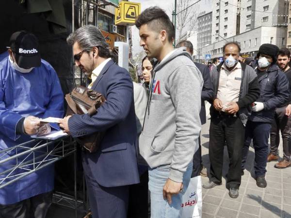 Orang ramai beratur untuk menerima pakej langkah berjaga-jaga yang disediakan oleh Basij, salah satu pasukan bersenjata Pengawal Revolusi Islam Iran di Teheran. - Foto AFP