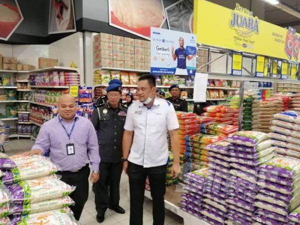 Mohd Ridzuan (kanan) meninjau bekalan makanan di Pasaraya Mydin Jalan Bharu tadi.