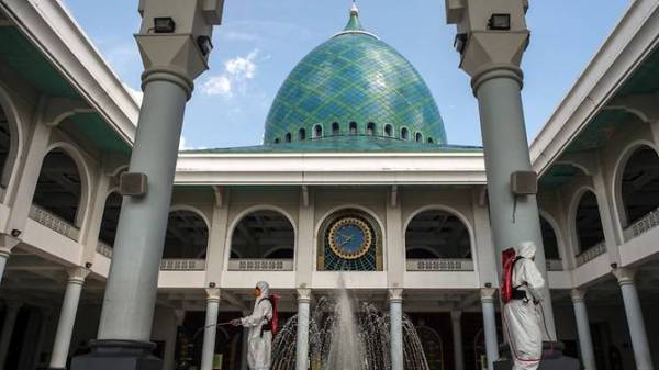 Pihak berkuasa kesihatan melakukan semburan nyahjangkit di sebuah masjid di Surabaya di Jawa Timur. - FOTO: AGENSI
