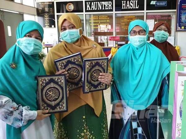 Zuraida (dua, kiri) ketika menyerahkan al-Quran kepada pesakit yang dikuarantin di Hospital Hulu Terengganu akibat penularan wabak Covid-19.