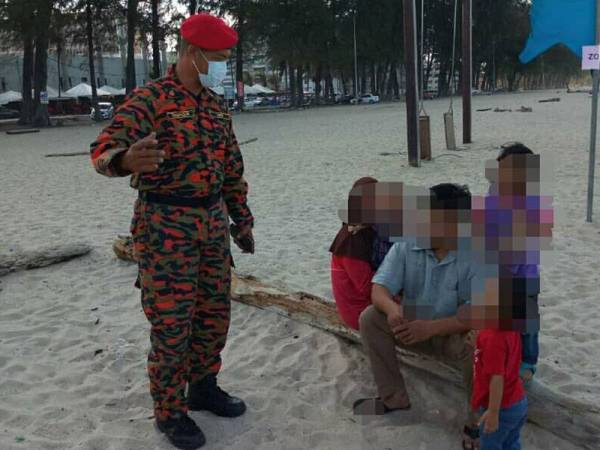 Anggota bomba menasihati pengunjung supaya beredar daripada lokasi pantai dan segera pulang ke rumah ketika rondaan, petang semalam. - FOTO: Ihsan Bomba