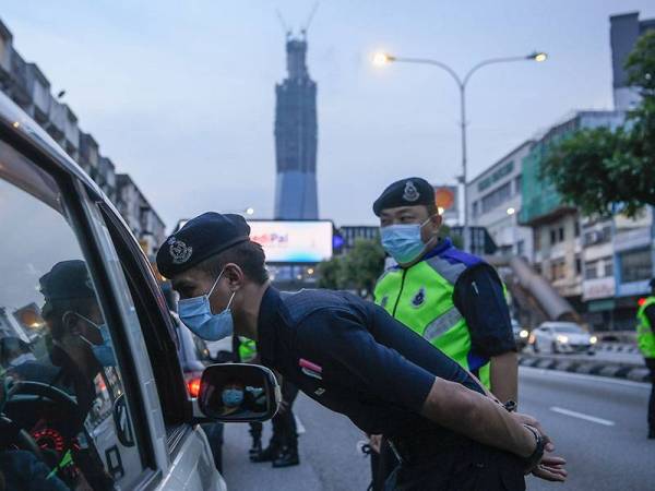 Anggota polis membuat pemeriksaan kenderaan bagi memastikan orang ramai mematuhi arahan berikutan tempoh Perintah Kawalan Pergerakan bermula semalam hingga 31 Mac ini di Jalan Loke Yew hari ini. -Foto Bernama