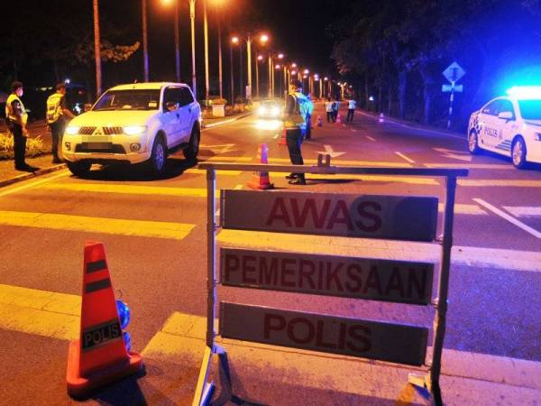 Anggota polis melakukan sekatan jalan raya susulan Perintah Kawalan Pergerakan selama 14 hari sehingga 31 Mac ini sebagai langkah pencegahan penularan Covid-19 di Jalan Tun Mustapha, Labuan malam tadi. - Foto Bernama
