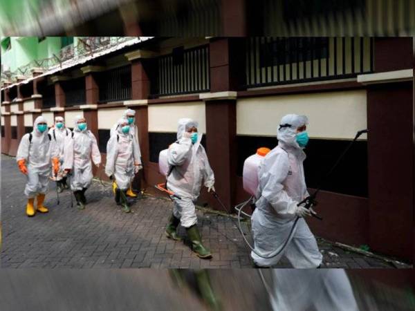 Sukarelawan dari Palang Merah Indonesia membawa penyembur disinfeksi di sebuah kompleks sekolah yang ditutup berikutan penularan Covid-19 di Jakarta. - Foto Reuters