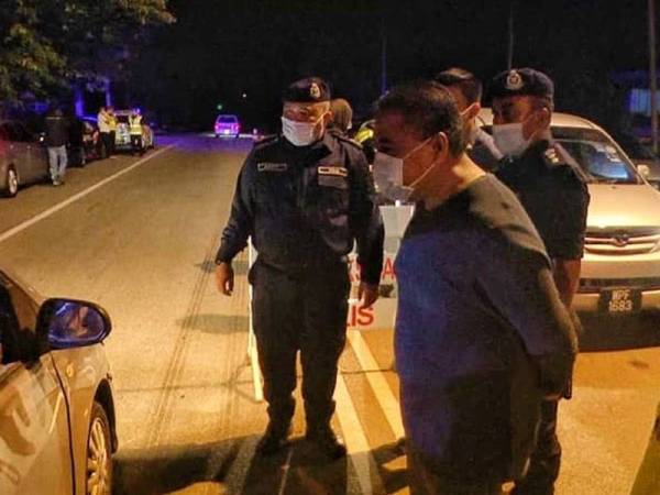 Ismail (tengah) bersama Mohd Yusri bertanyakan sesuatu kepada pemandu ketika sekatan jalan raya sepanjang Perintah Kawalan Pergerakan berjalan di Lubuk Kawah, Temerloh malam tadi.