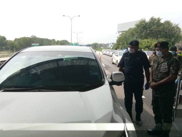 Norsham (kanan) memantau sekatan jalan raya di Bukit Jelutong hari ini.