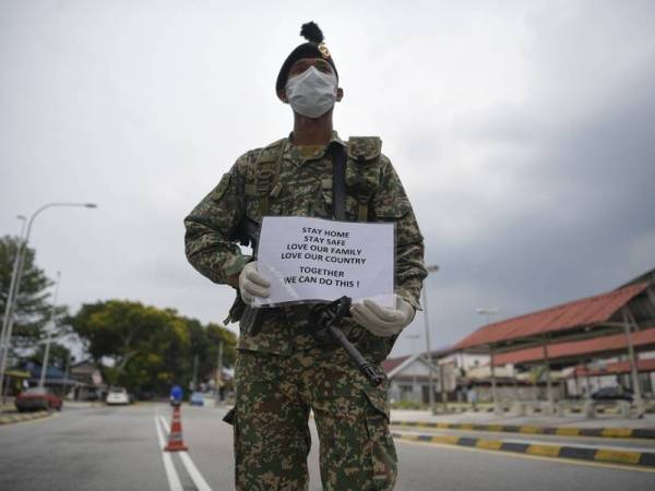 Seorang anggota Angkatan Tentera Malaysia (ATM) lengkap memakai topeng muka menunjukkan plakad peringatan untuk kekal di rumah ketika memulakan tugasan membantu pihak polis dalam sekatan jalan raya susulan Perintah Kawalan Pergerakan (PKP) di sekitar ibu kota hari ini.
Anggota tentera mula membantu polis melaksanakan PKP mulai 12 tengah hari semalam. - Foto Bernama