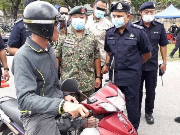 Ayob Khan (kanan) dan Zawai Adam (tengah) melakukan pemeriksaan terhadap orang ramai dalam satu sekatan jalan raya yang dibuat pihak polis dengan kerjasama ATM di Jalan Tampoi Lama, Johor Bahru, hari ini.