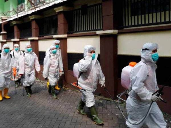 Sukarelawan dari Palang Merah Indonesia membawa penyembur disinfeksi di sebuah kompleks sekolah yang ditutup berikutan penularan Covid-19 di Jakarta. - Foto Reuters