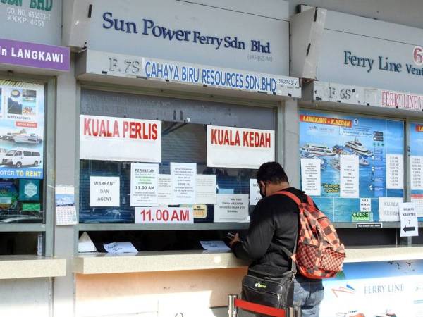 Seorang penumpang membeli tiket feri di Terminal Feri Penumpang Kuah di sini hari ini. -Foto Bernama