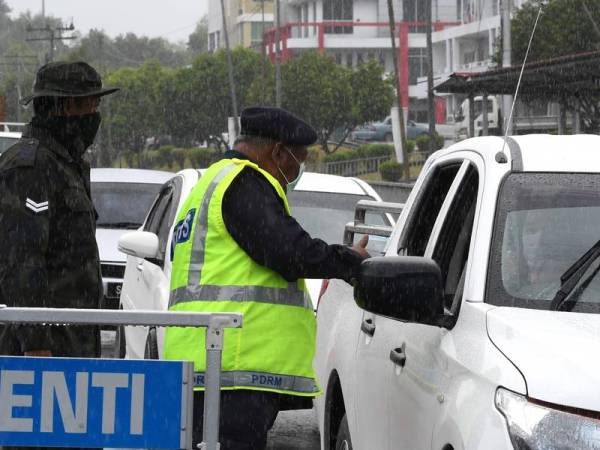 Anggota Polis dan Tentera tetap membuat sekatan jalan raya untuk mengawal pergerakan penduduk walaupun dalam keadaan cuaca hujan di Jalan Labuk hari ini. Anggota Polis dan Tentera mengadakan sekatan jalan raya di beberapa kawasan di daerah ini berikutan arahan Perintah Kawalan Pergerakan sehingga 31 Mac ini bagi mengekang penularan COVID-19. - Foto Bernama
