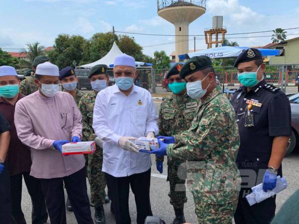 Ahmad (kiri) menyerahkan makanan kepada anggota ATM yang bertugas di Pasir Pekan.