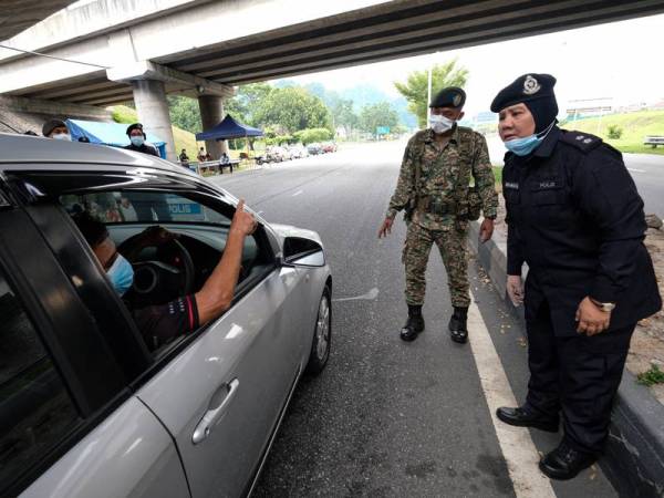 Anggota tentera membantu polis ketika mengadakan sekatan jalan raya bagi memastikan rakyat mematuhi Perintah Kawalan Pergerakan (PKP). -Foto Bernama