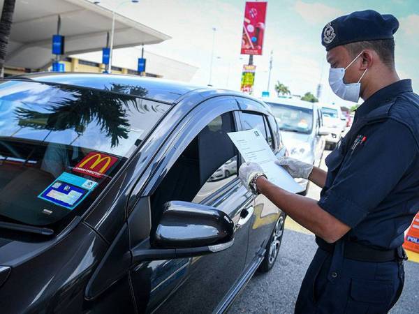 Anggota Polis giat memeriksa surat yang dikeluarkan majikan ketika tinjauan berkenaan Perintah Kawalan Pergerakan (PKP) yang masuk hari ketujuh hari ini. -Foto Bernama