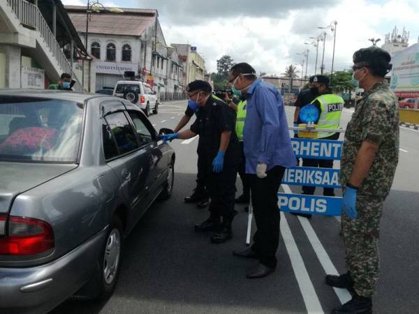 Amran (kiri) bertanya sesuatu kepada pengguna jalan raya sambil diperhatikan Mohd Faizal (dua dari kanan) ketika melakukan lawatan di kawasan sekatan jalan raya di Pekan Kuala Pilah.