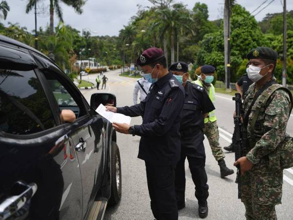 Anggota tentera membantu polis ketika mengadakan sekatan jalan raya bagi memastikan rakyat mematuhi Perintah Kawalan Pergerakan (PKP). - Foto Bernama