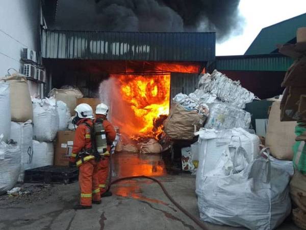 Anggota bomba memadamkan kebakaran dua kilang di kawasan perindustrian Kundang tengah hari tadi