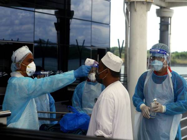 Petugas Kementerian Kesihatan Malaysia (KKM) memeriksa suhu badan lapan Jemaah Tabligh dari Makassar dan Jakarta yang tiba di Terminal Feri Antarabangsa Puteri Harbour hari ini diperiksa taraf kesihatan sebagai langkah mencegah penularan COVID-19. FOTO: BERNAMA