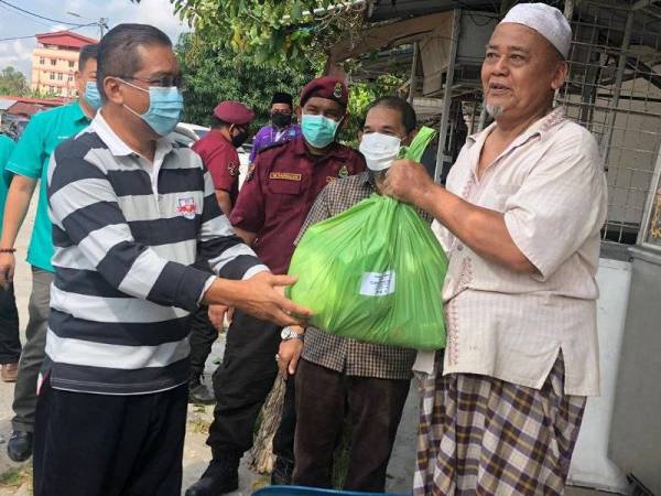 Takiyuddin (kiri) semasa menyampaikan bantuan kepada penduduk di kawasan Kota Bharu.